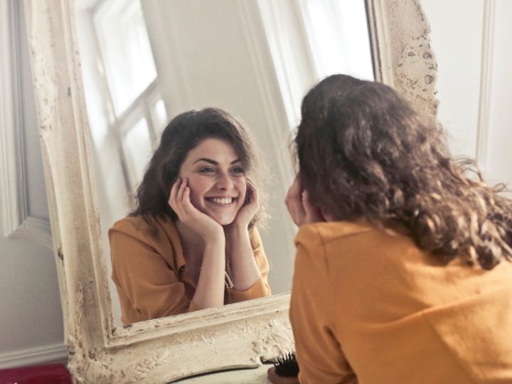 鏡を見てほほ笑む女性