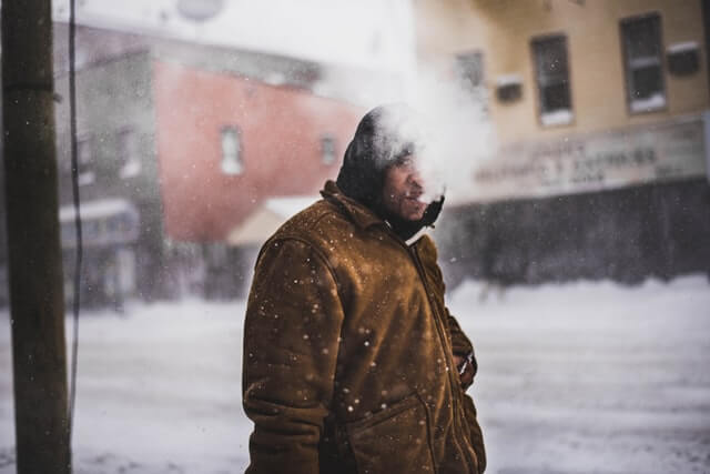 雪の中タバコを吸う男性