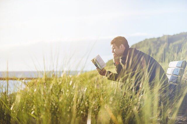 草原で読書する男性